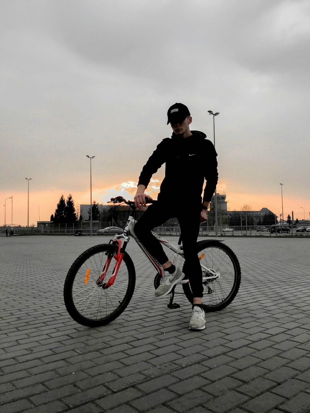 낮 동안 회색 포장 도로에서 자전거를 타는 검은 재킷을 입은 남자