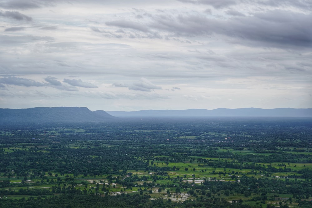 green trees and mountains under white clouds during daytime