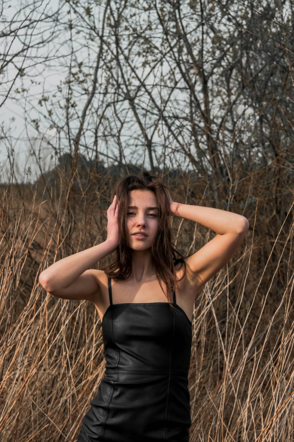 woman in black spaghetti strap top standing on brown grass field during daytime