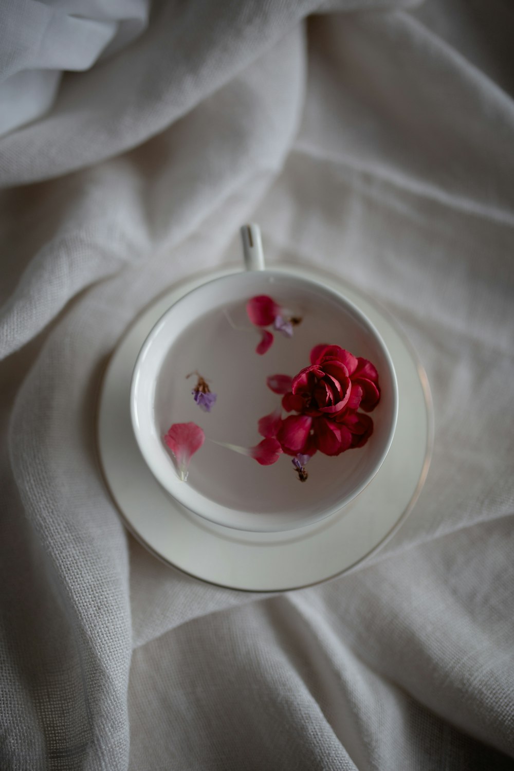 white and pink floral ceramic bowl on white textile