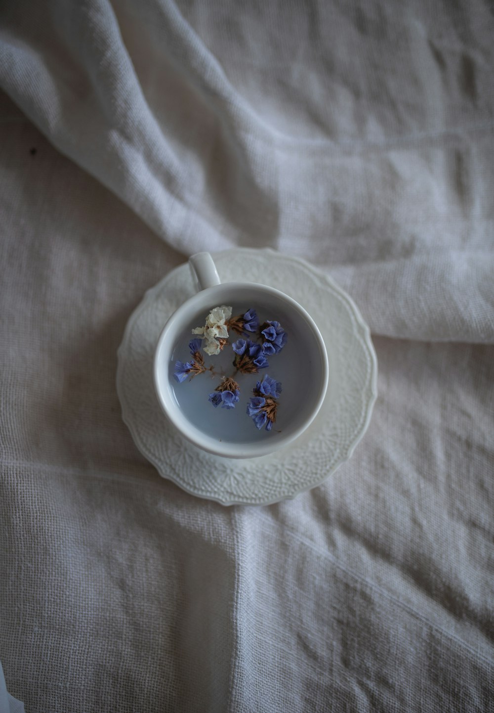white and blue floral ceramic teacup on white textile