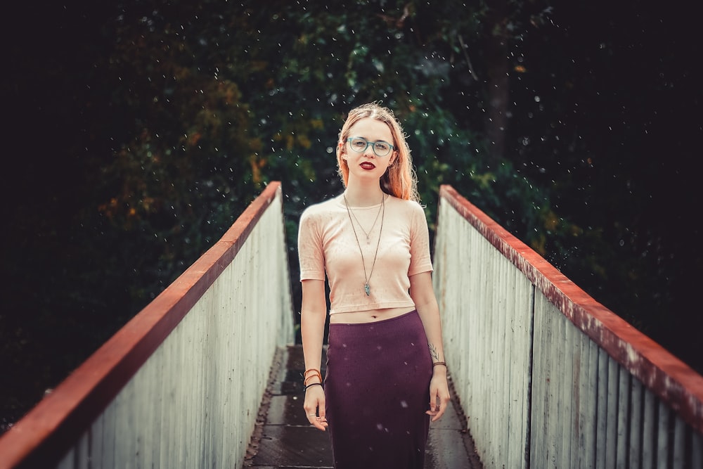 woman in black spaghetti strap dress standing on wooden bridge