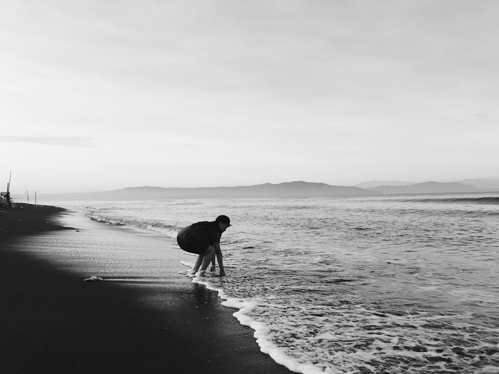 grayscale photo of man and woman walking on beach