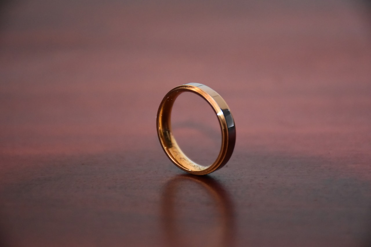 types of wedding bands shown by a beveled two-tone men's band on a wood surface