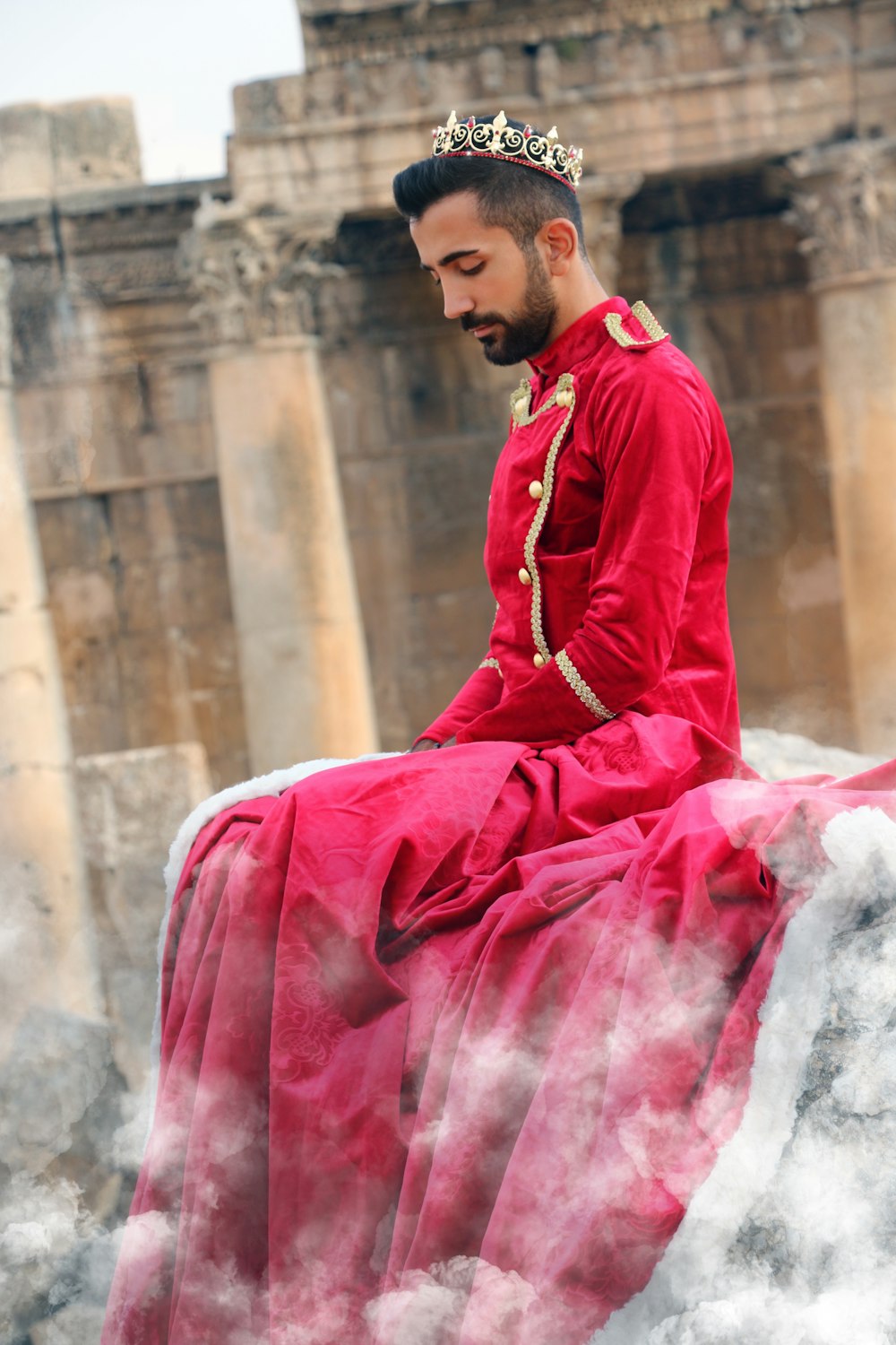 man in red long sleeve dress sitting on white textile