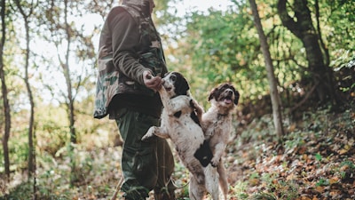 man in black leather jacket holding white and black short coated dog