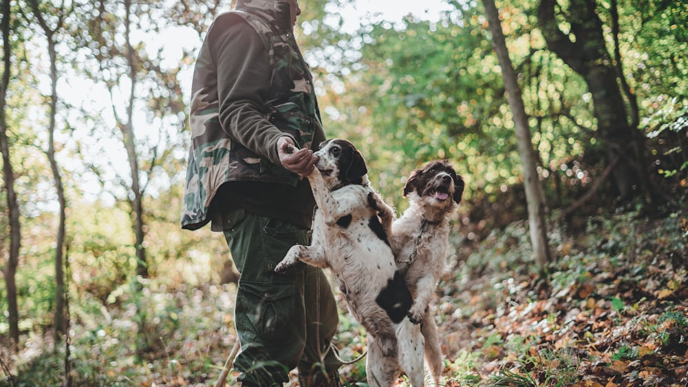 Homme en veste en cuir noir tenant un chien à poil court blanc et noir