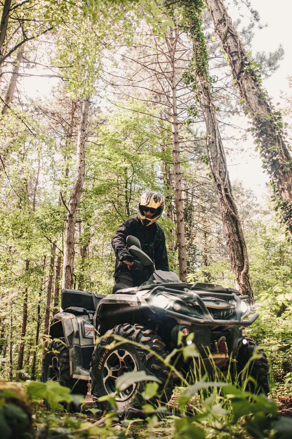 man riding on black motorcycle in forest during daytime