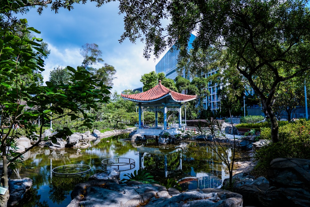 brown and white wooden gazebo near green trees and river during daytime