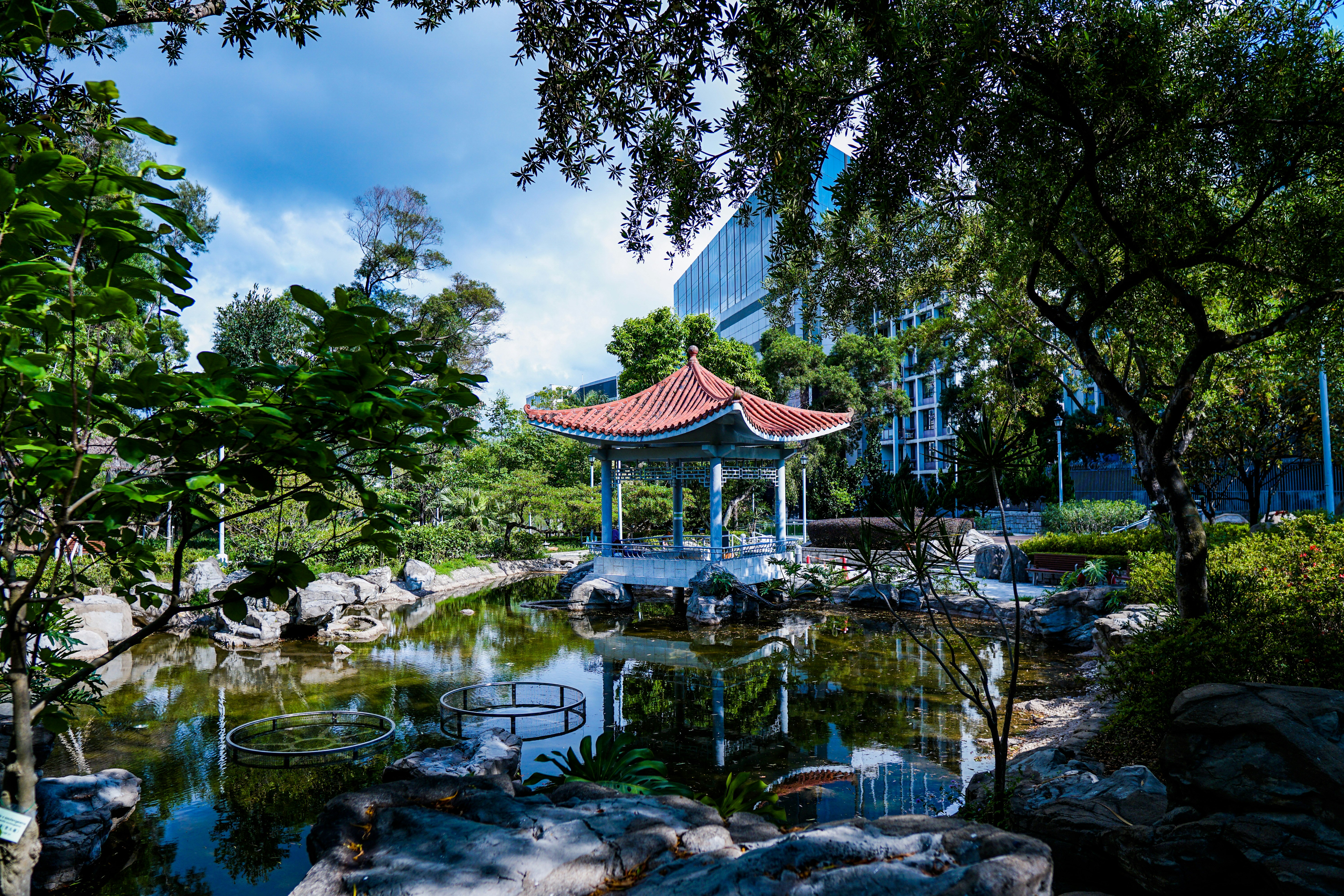 brown and white wooden gazebo near green trees and river during daytime