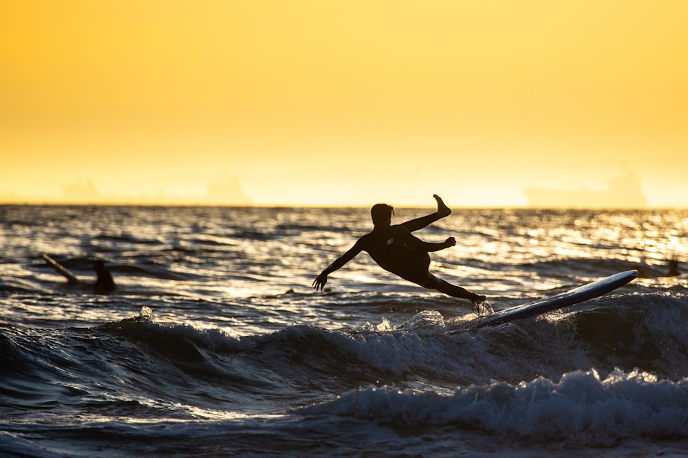 man surfing on sea waves during sunset