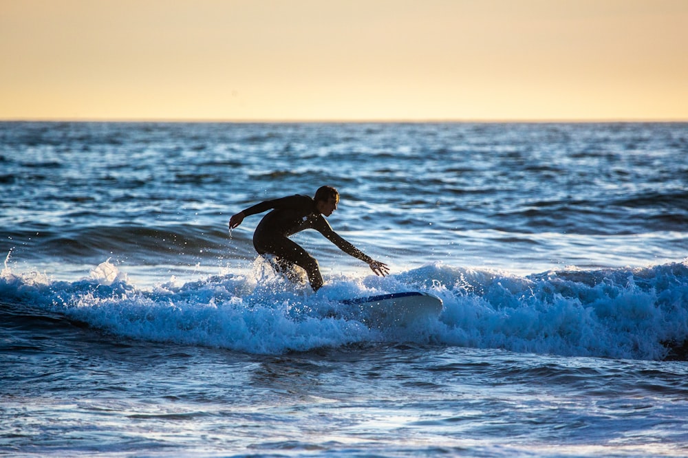 man surfing on sea waves during sunset