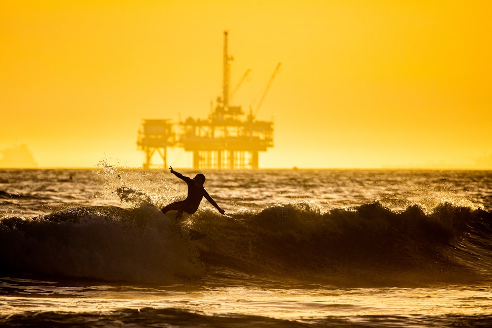 man surfing on sea waves during sunset