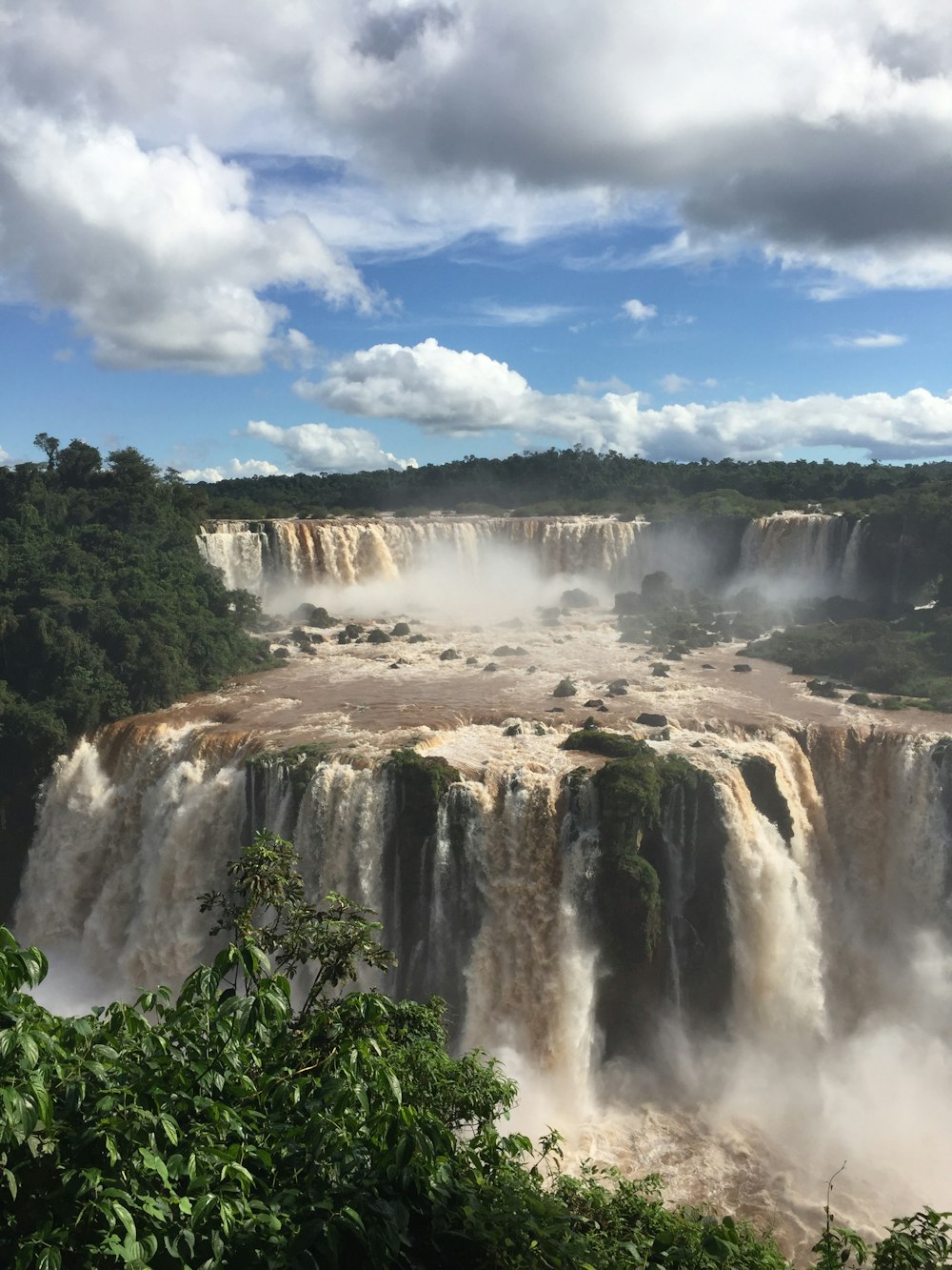 waterfalls under blue sky and white clouds during daytime