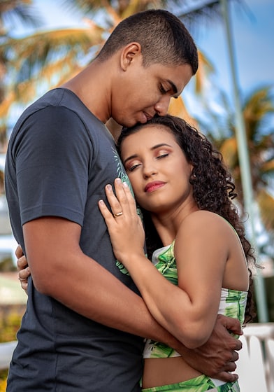 man in black crew neck t-shirt kissing woman in green tank top