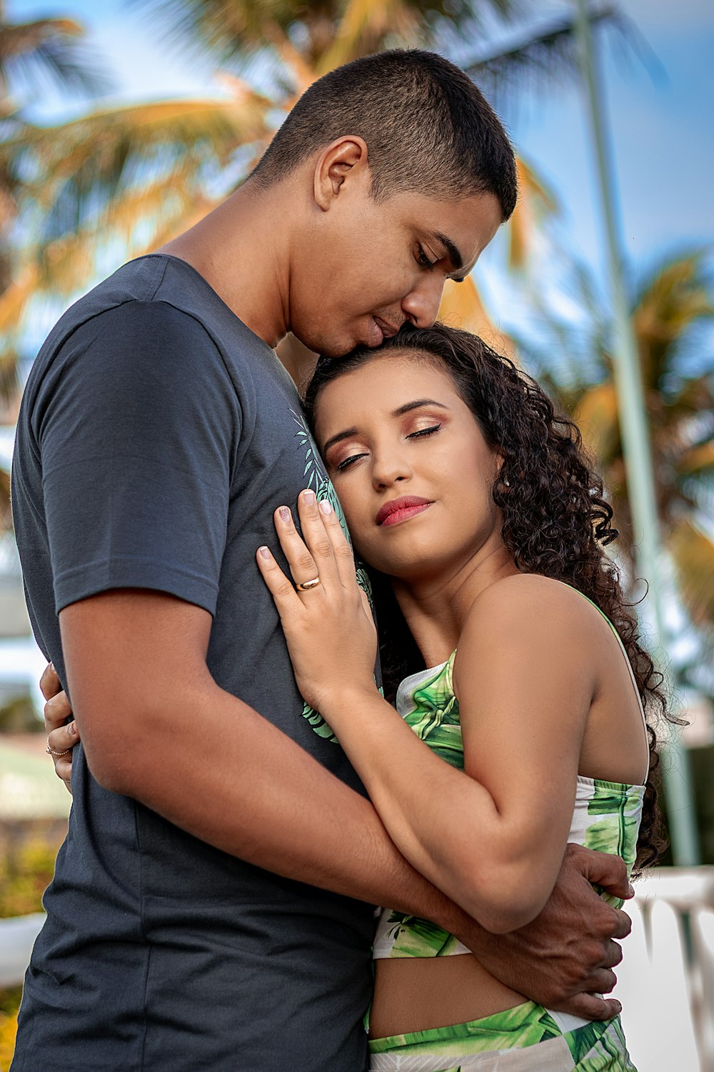 man in black crew neck t-shirt kissing woman in green tank top