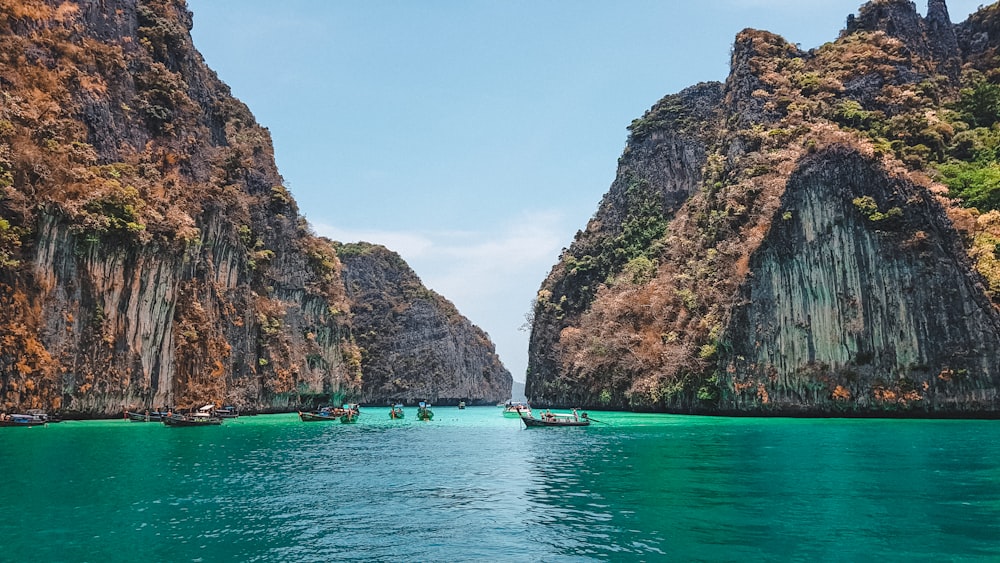 boat on water near brown rock formation during daytime