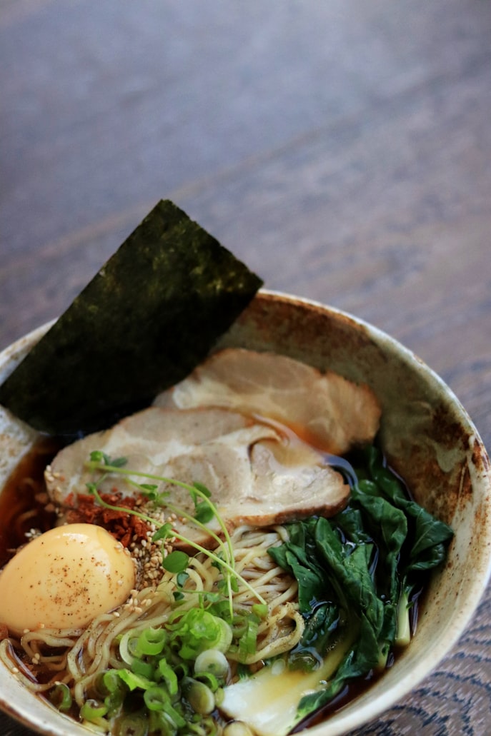 a bowl of ramen with pork and eggs with greens|500