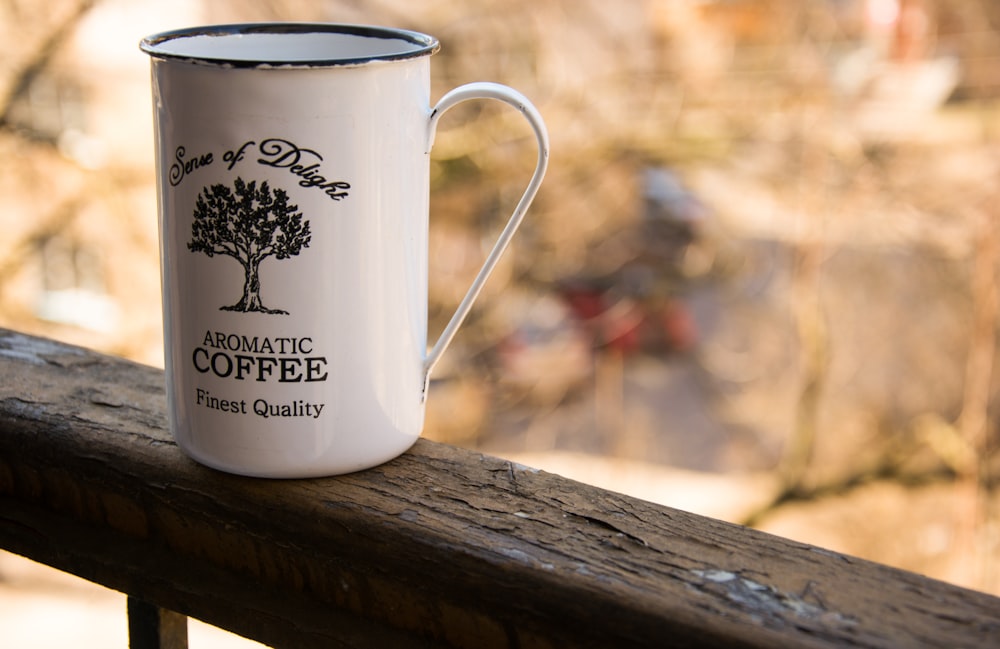 white and black ceramic mug on brown wooden table