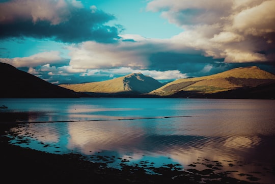 body of water near mountain under cloudy sky during daytime in Loch Fyne United Kingdom