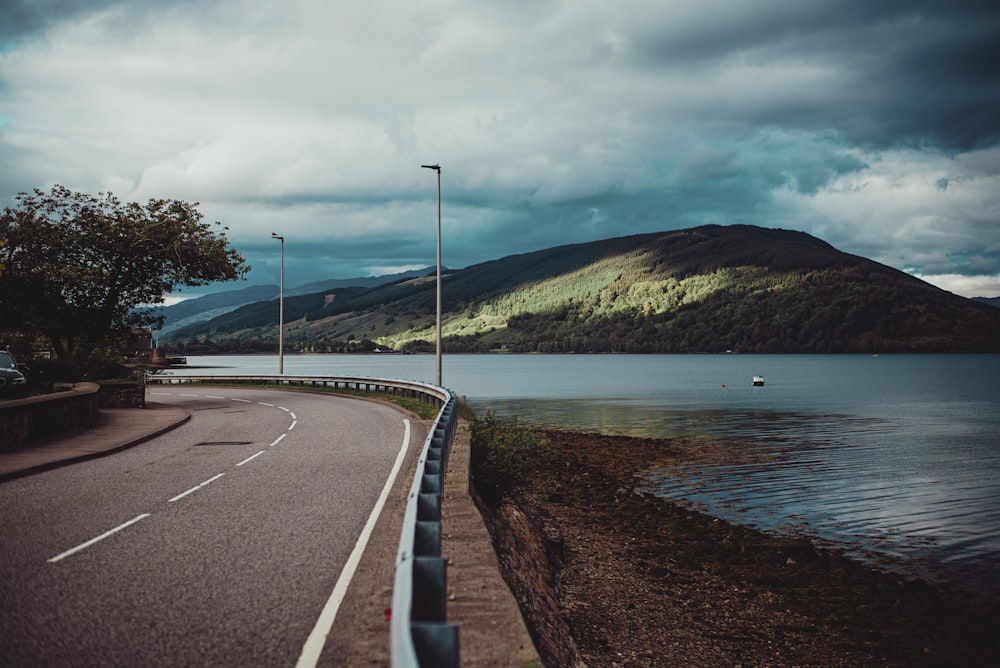 gray concrete road near body of water during daytime