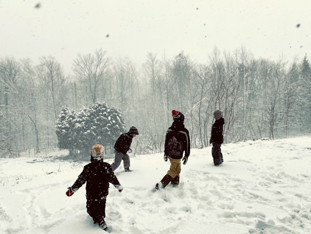 Children playing outside in colorful Christmas hats and scarves.