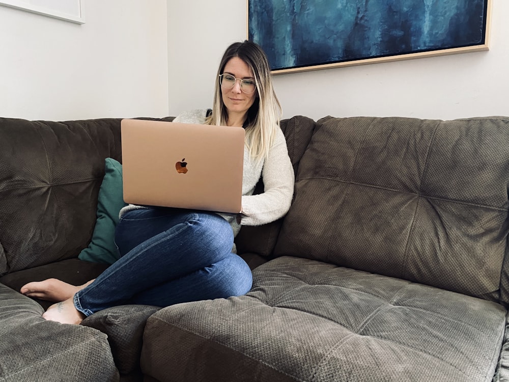 woman in blue denim jeans sitting on gray sofa