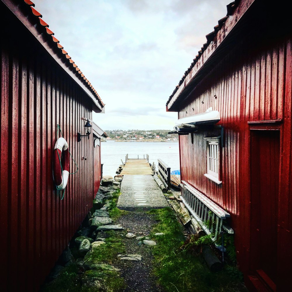 red wooden house near body of water under white clouds during daytime
