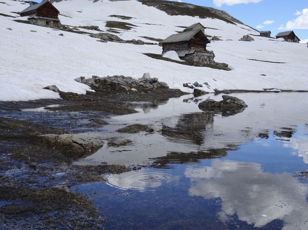 brown house on snow covered ground near body of water during daytime