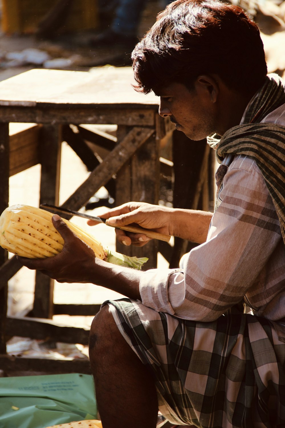 man in brown and white plaid dress shirt and brown pants sitting on brown wooden bench