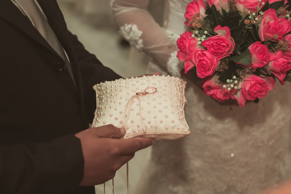 person holding white and pink floral textile