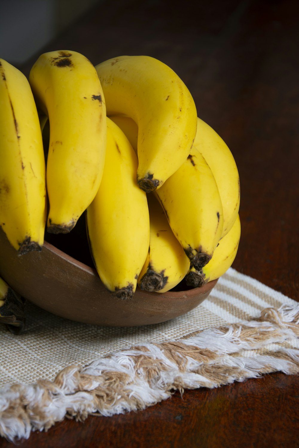 Frutto di banana giallo su ciotola di legno marrone