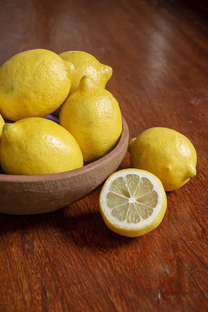 Fresh lemons in a rustic bowl on a warm wooden table