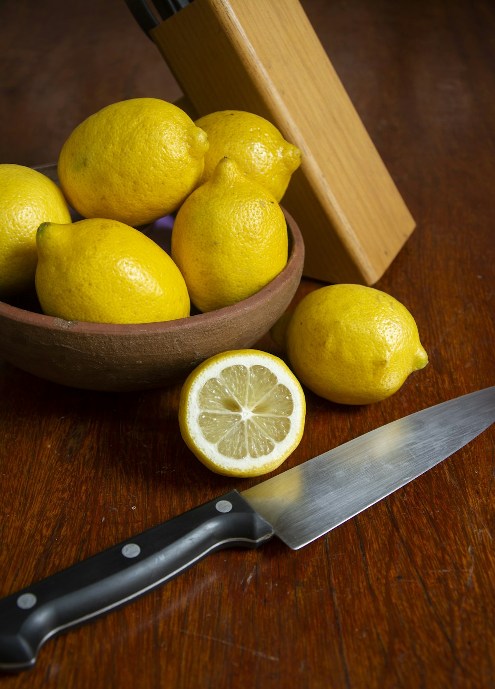 sliced lemon beside black handled knife on brown wooden table