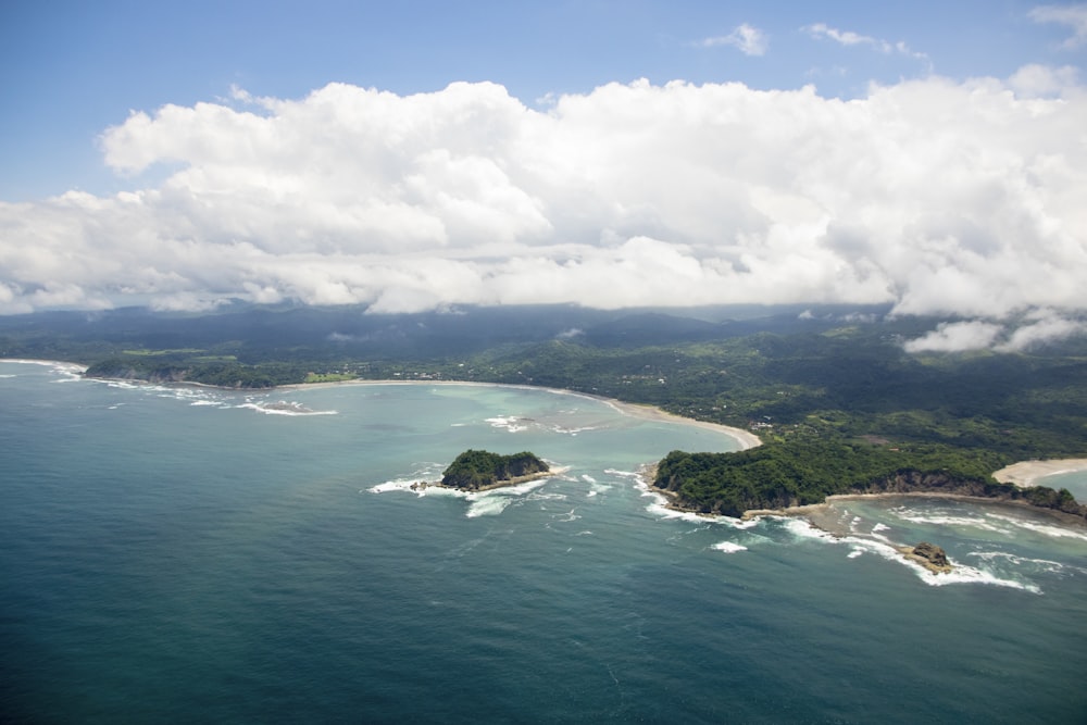 green island in the middle of ocean under white clouds and blue sky during daytime