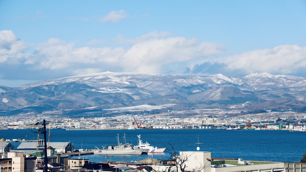 navire blanc et noir sur la mer près de la montagne sous les nuages blancs pendant la journée