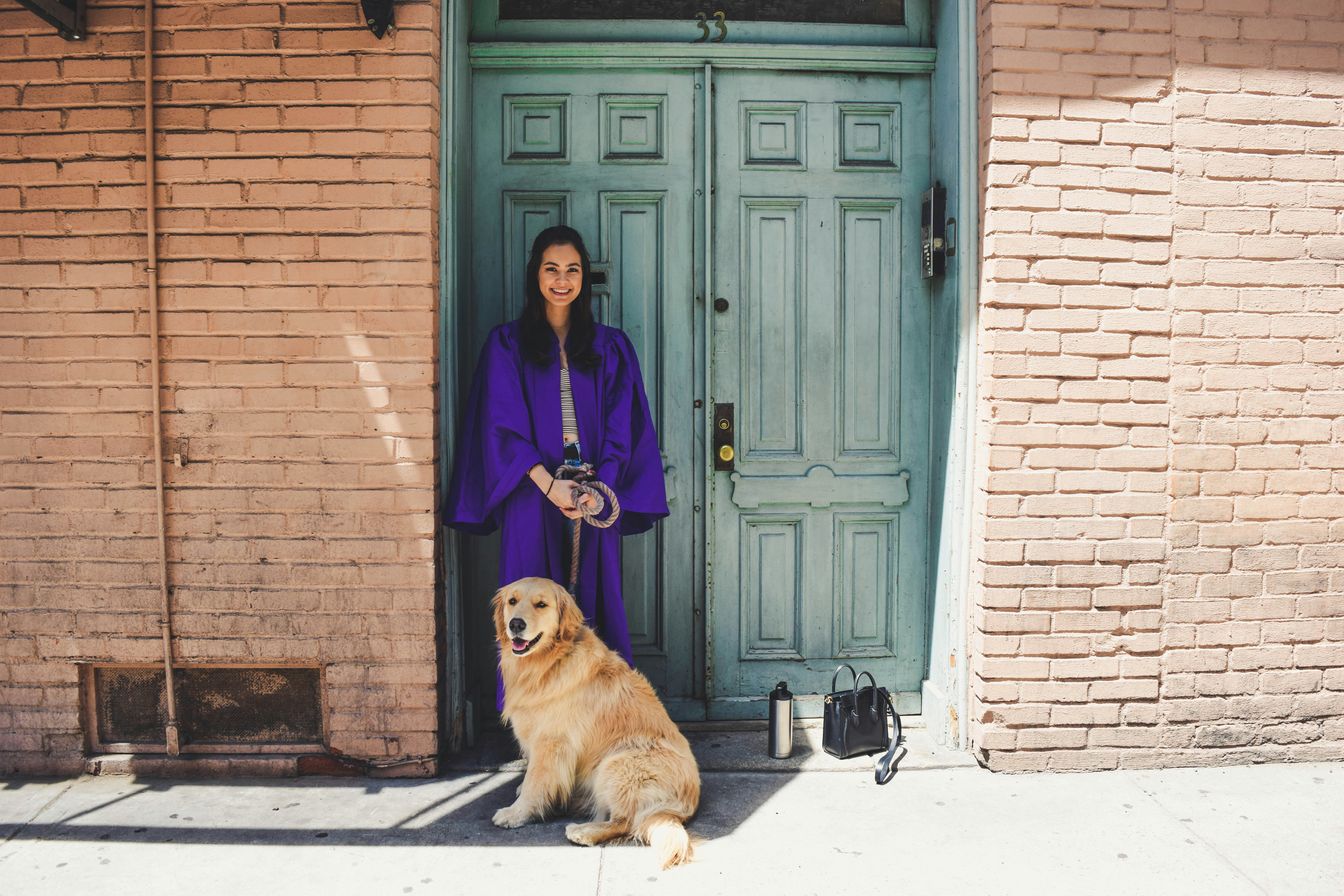 woman in blue coat standing beside brown brick wall