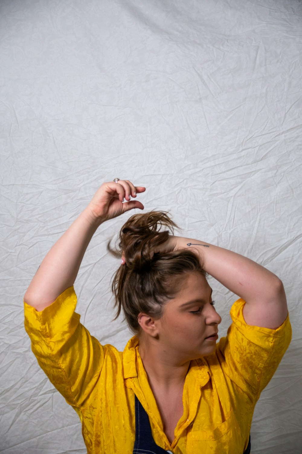 woman in yellow crew neck t-shirt holding her hair