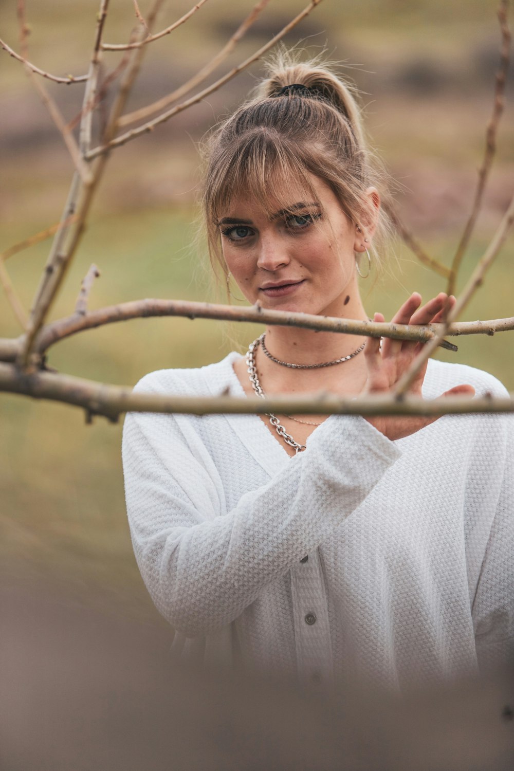 woman in white sweater holding brown stick