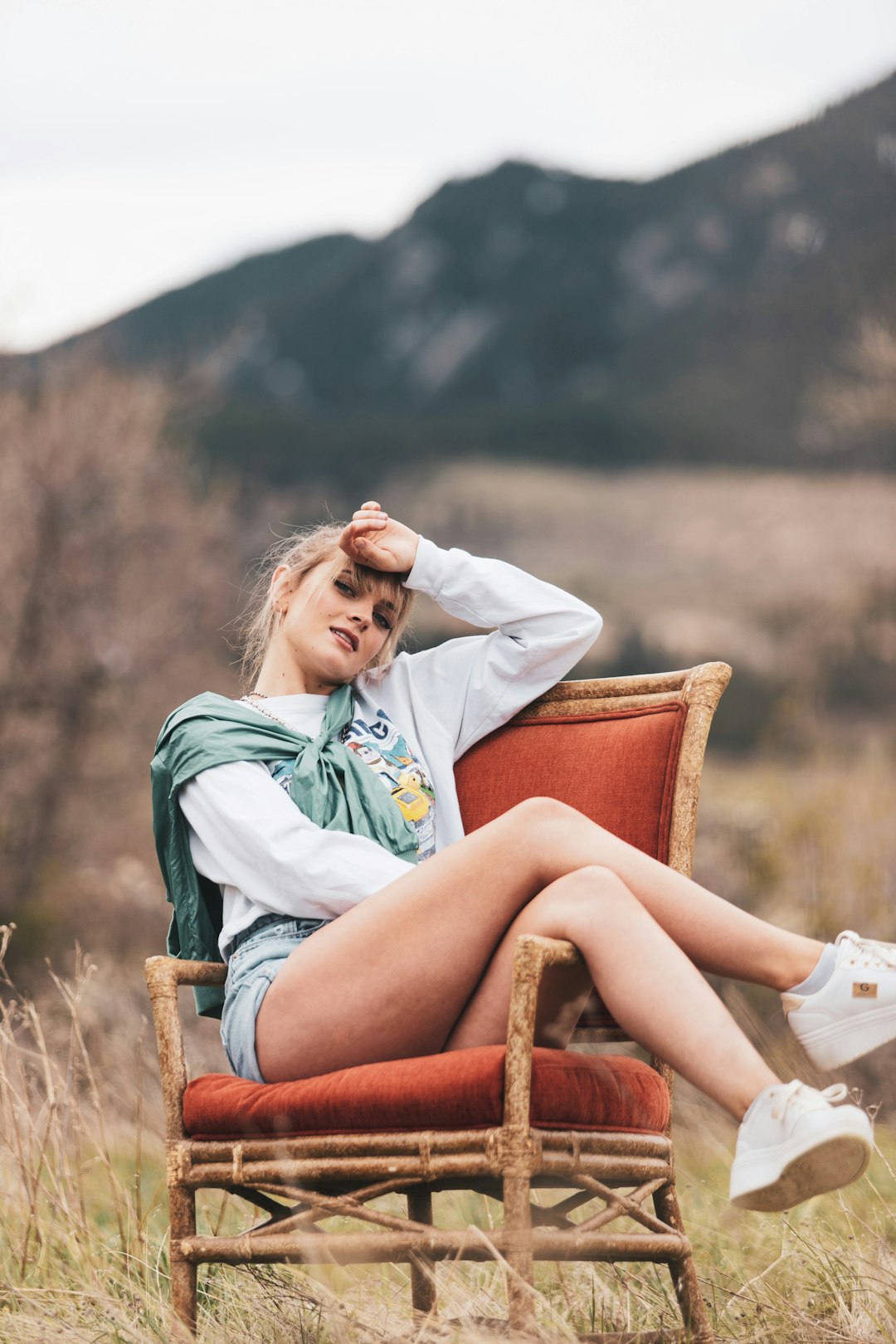 woman in white and green floral long sleeve shirt sitting on brown wooden armchair