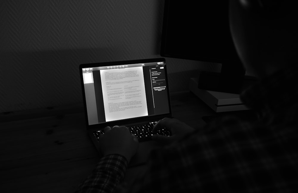 grayscale photo of person using macbook pro