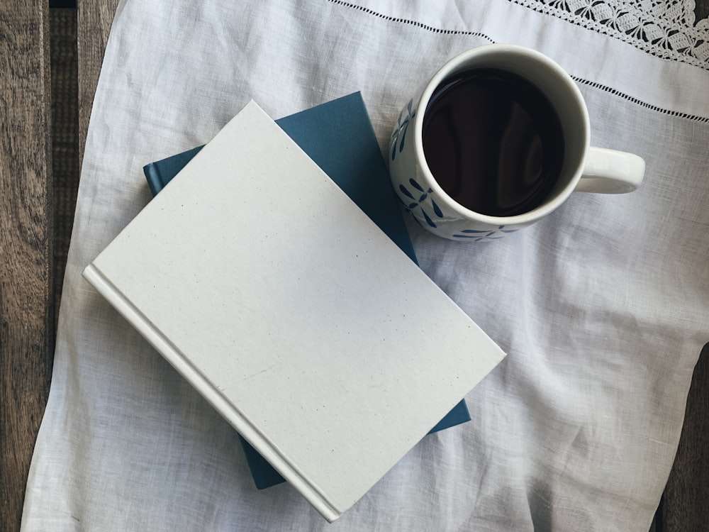 Papier blanc à côté d’une tasse en céramique blanche