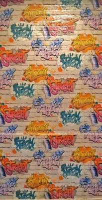 A vibrant graffiti mural covers a brick wall. Various words like 'Spray', 'Street', and 'Swag' are depicted in bright colors, including yellow, pink, blue, orange, and green, with artistic flair and dynamic styles. The background features a realistic brick texture with splashes of color surrounding the text.
