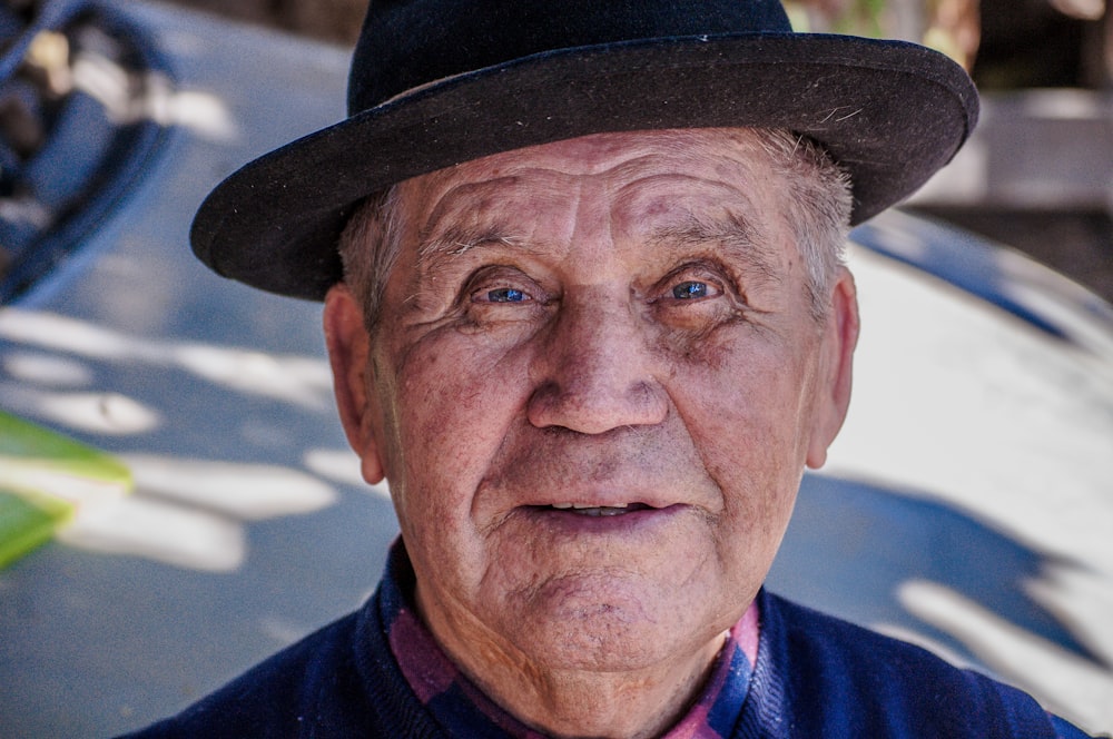 man in blue and white collared shirt wearing brown fedora hat