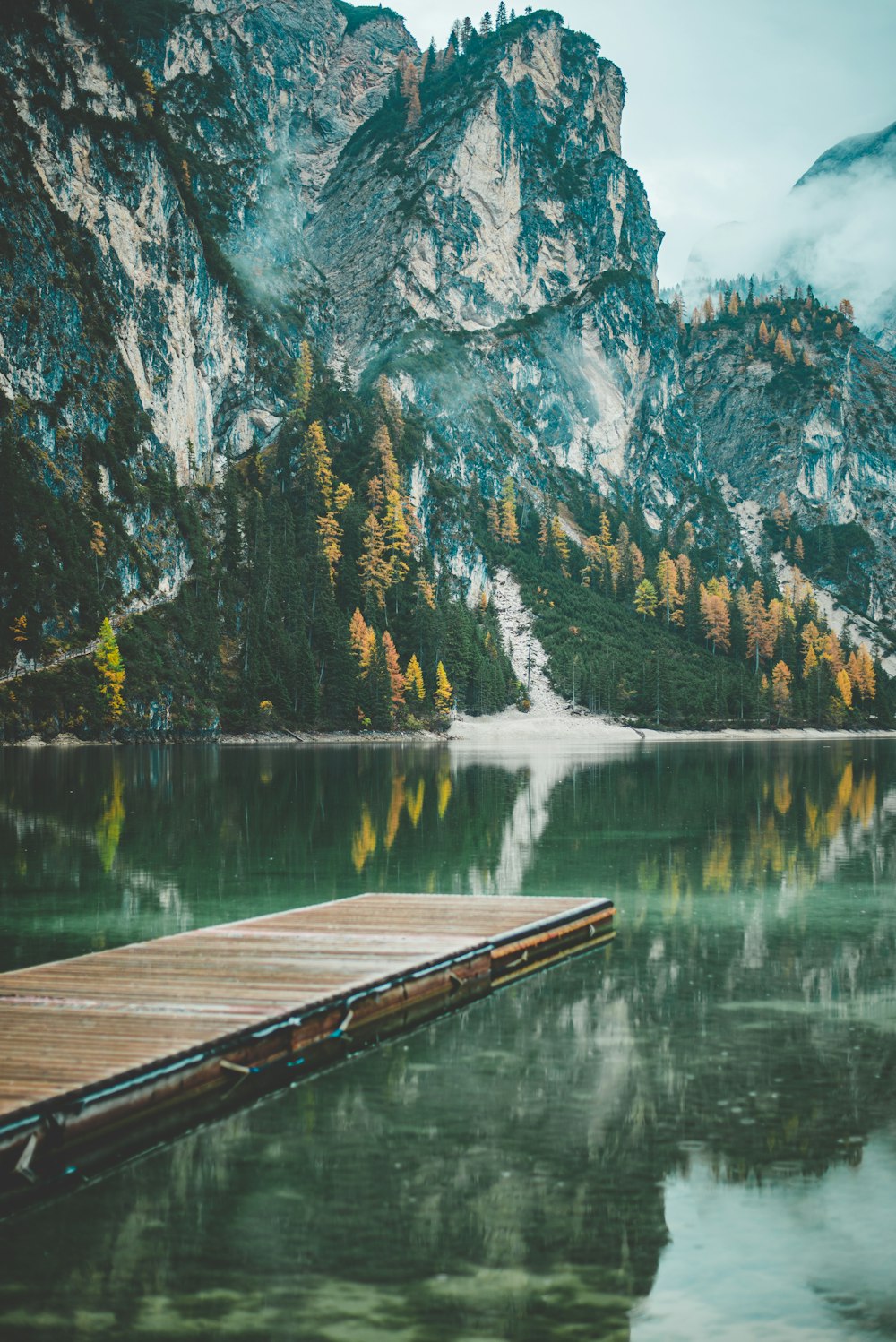 Muelle de madera marrón en el lago cerca de la montaña