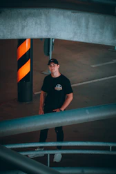 man in black crew neck t-shirt standing beside gray metal railings