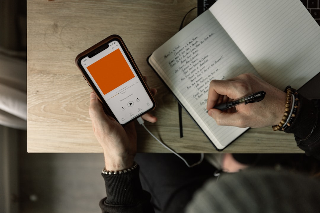 Man listening to a podcast and making notes to a notepad