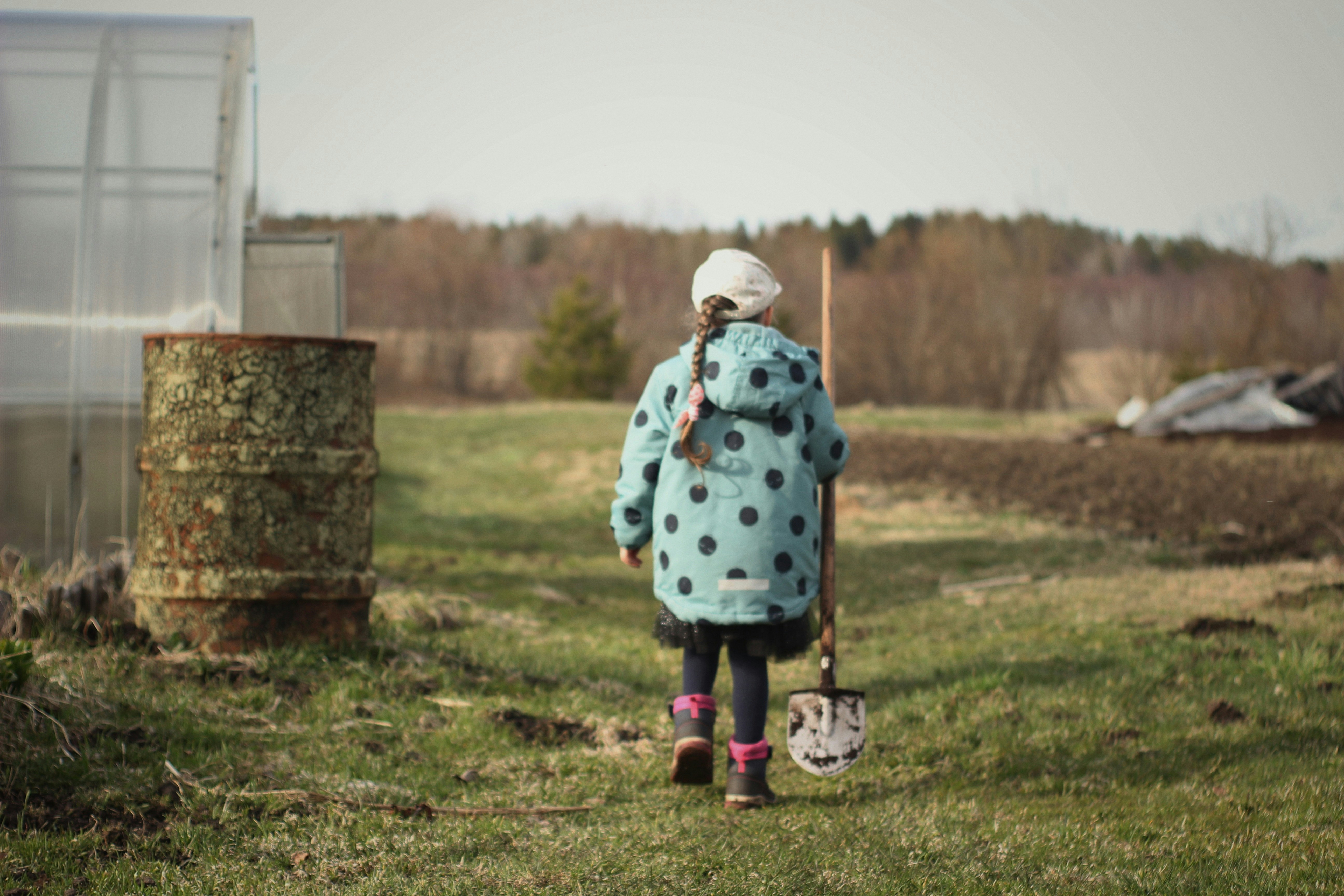 girl in blue and white polka dot dress standing on green grass field during daytime