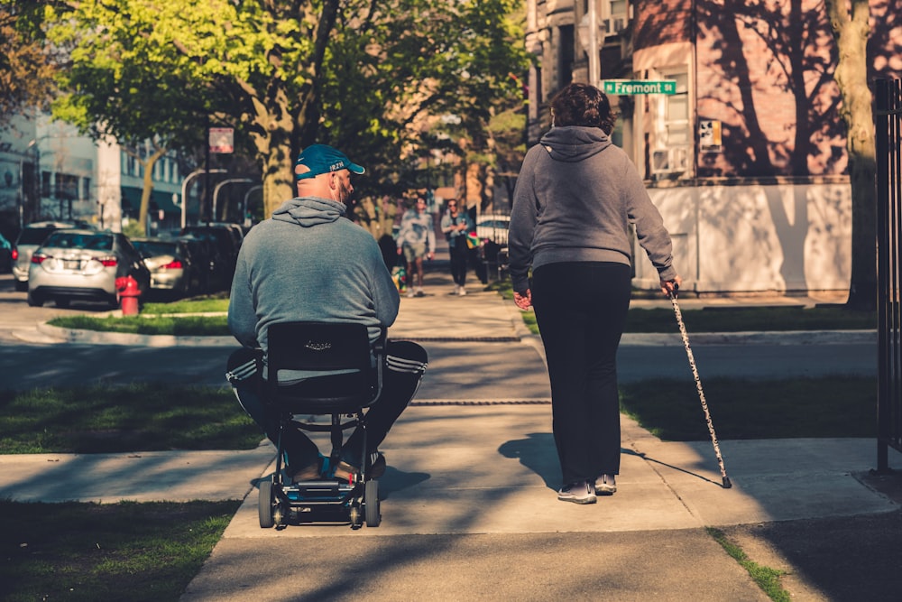 man in gray hoodie and black pants sitting on black and gray stroller during daytime