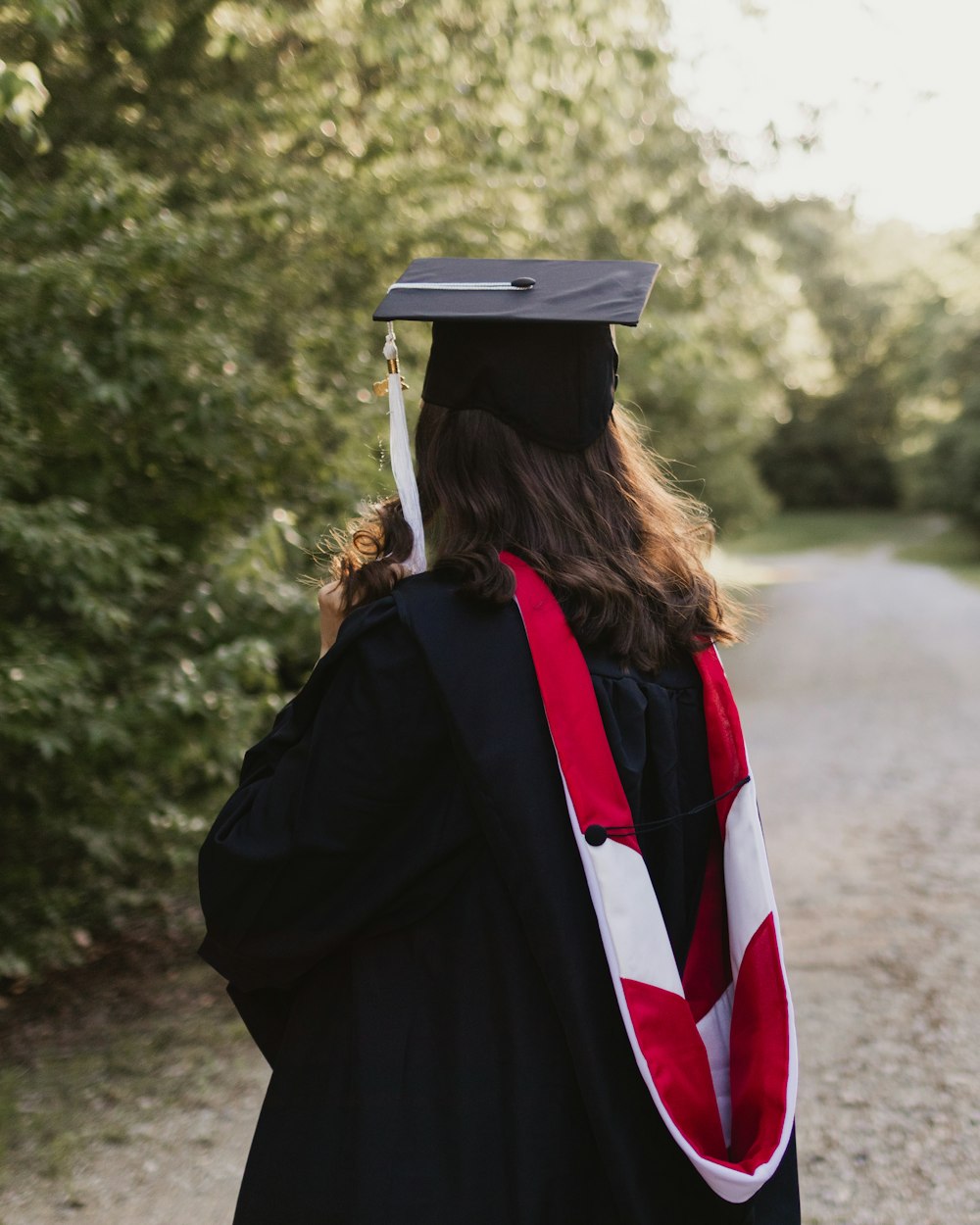 woman in academic dress and academic hat standing on dirt road during daytime